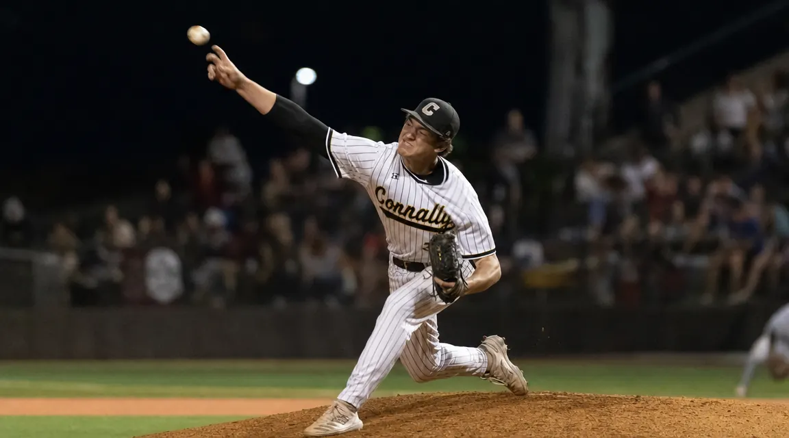 Teen pitcher mid-delivery at full arm extension, elbow sleeve visible, stadium lights in background suggesting a game evening