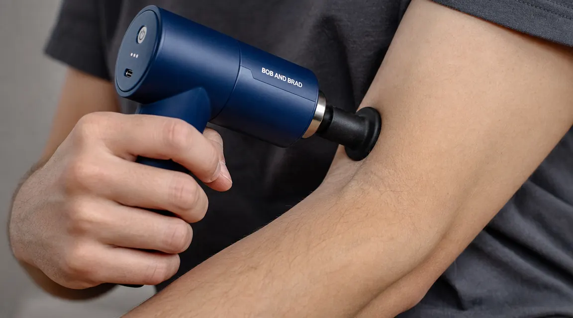 Close-up of a massage gun attachment head positioned just below the elbow on a pitcher's inner arm