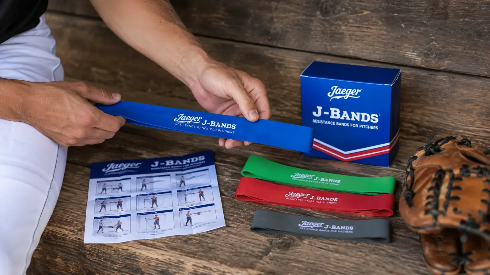 Close-up of Jaeger J-Bands resistance bands coiled on a dugout bench next to a baseball glove